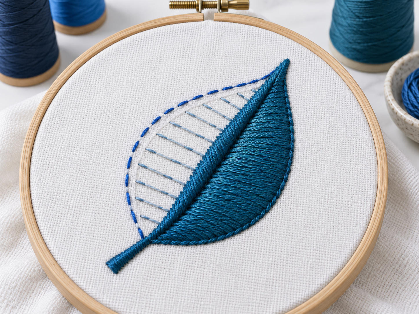 Close view of a leaf embroidery sample showing an outline, supporting stitches, satin edging, and fill stitches